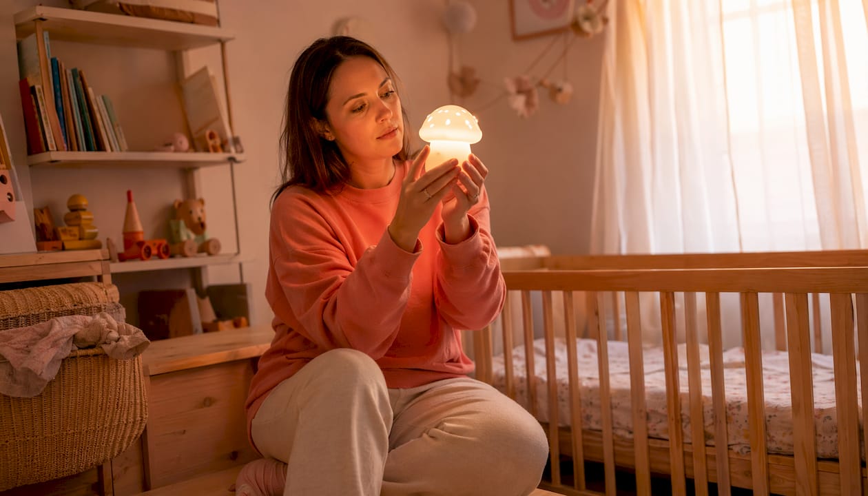 Une maman vérifie la veilleuse de son bébé dans la chambre d’enfant.