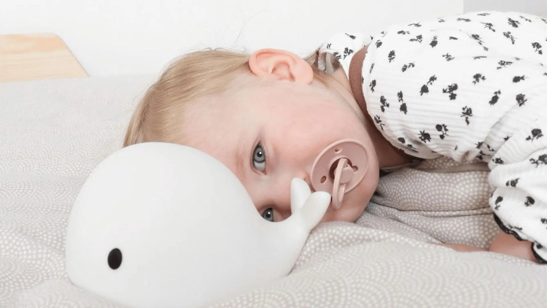 Veilleuse baleine apaisante diffusant une douce lumière près d’un enfant dans son lit pour favoriser un sommeil paisible.
