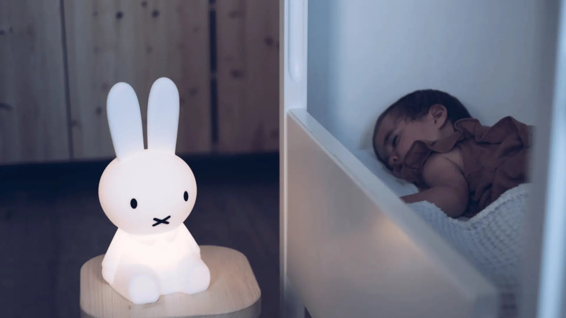 Enfant qui dort paisiblement à côté d’une veilleuse bébé diffusant une lumière douce et rassurante.